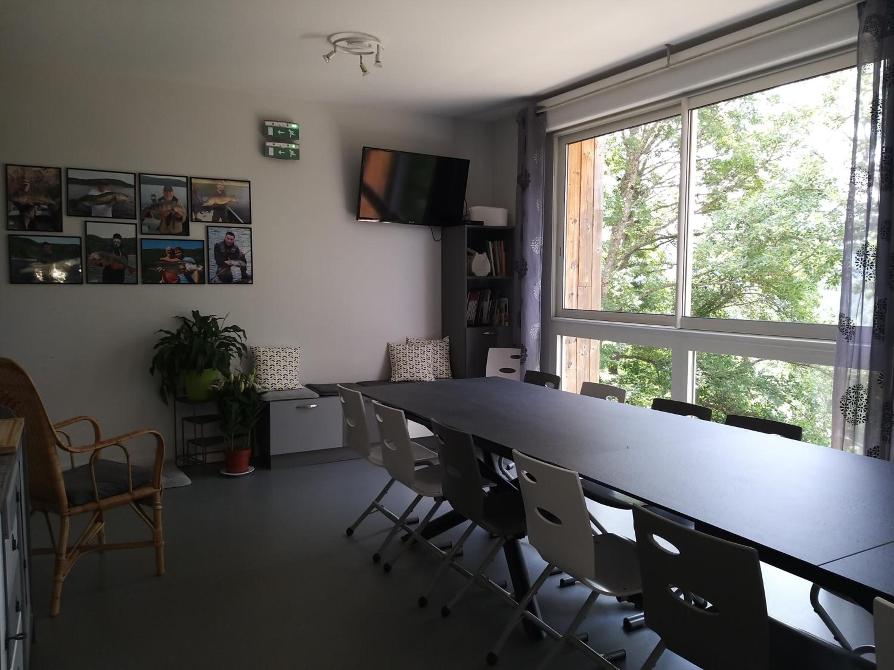 A conference room with a long table, chairs, a TV, and a bookshelf.