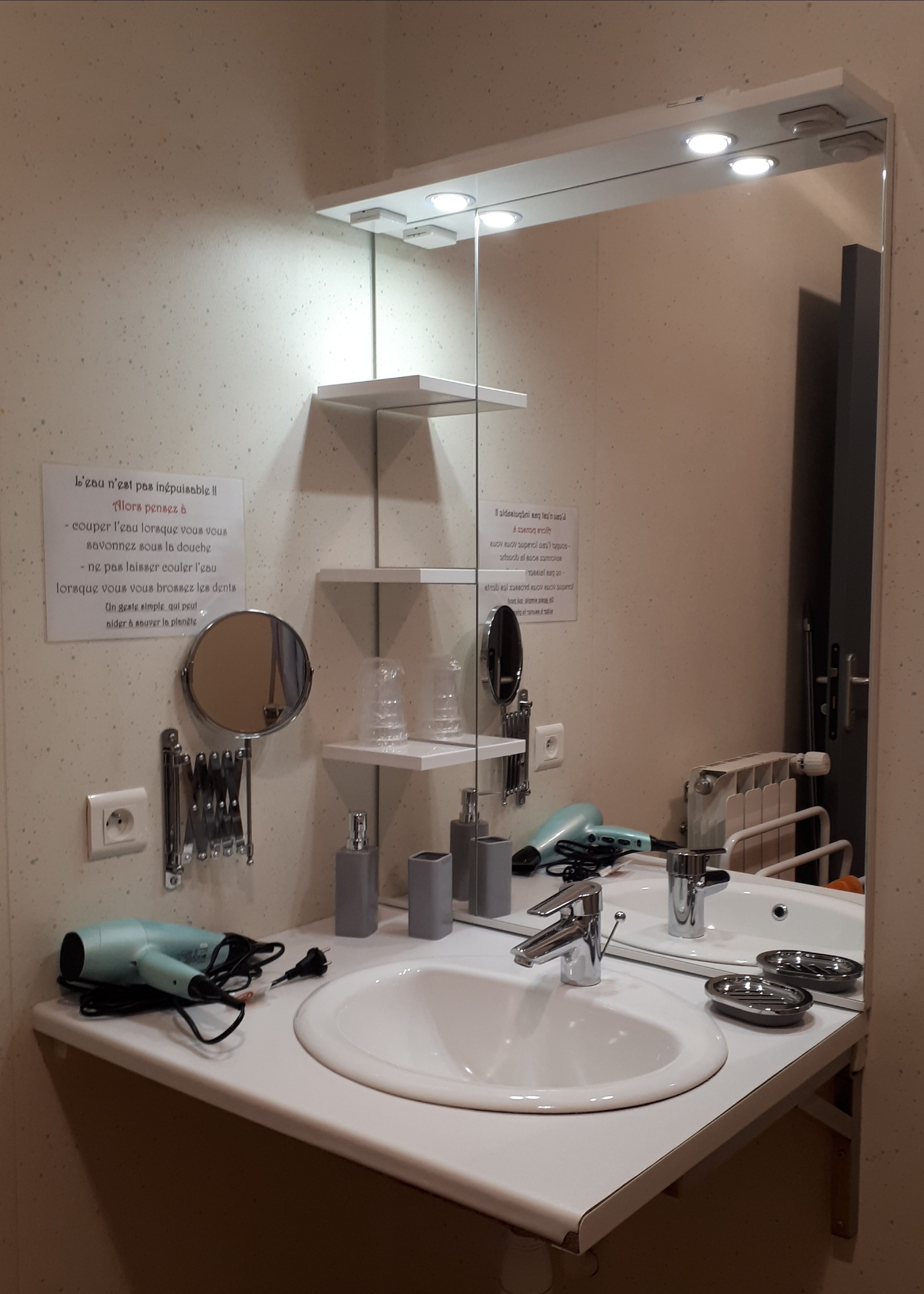 A bathroom with a white sink, mirror, and shelves. There are toiletries and a hairdryer on the counter.
