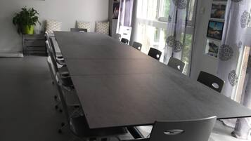 Un salón de conferencias con una larga mesa, sillas, un televisor y una planta en maceta.