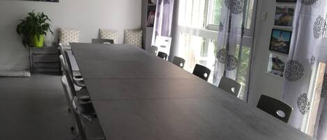 Ein Konferenzraum mit langem Tisch, Stühlen, einem Fernseher und einem Blumentopf.
