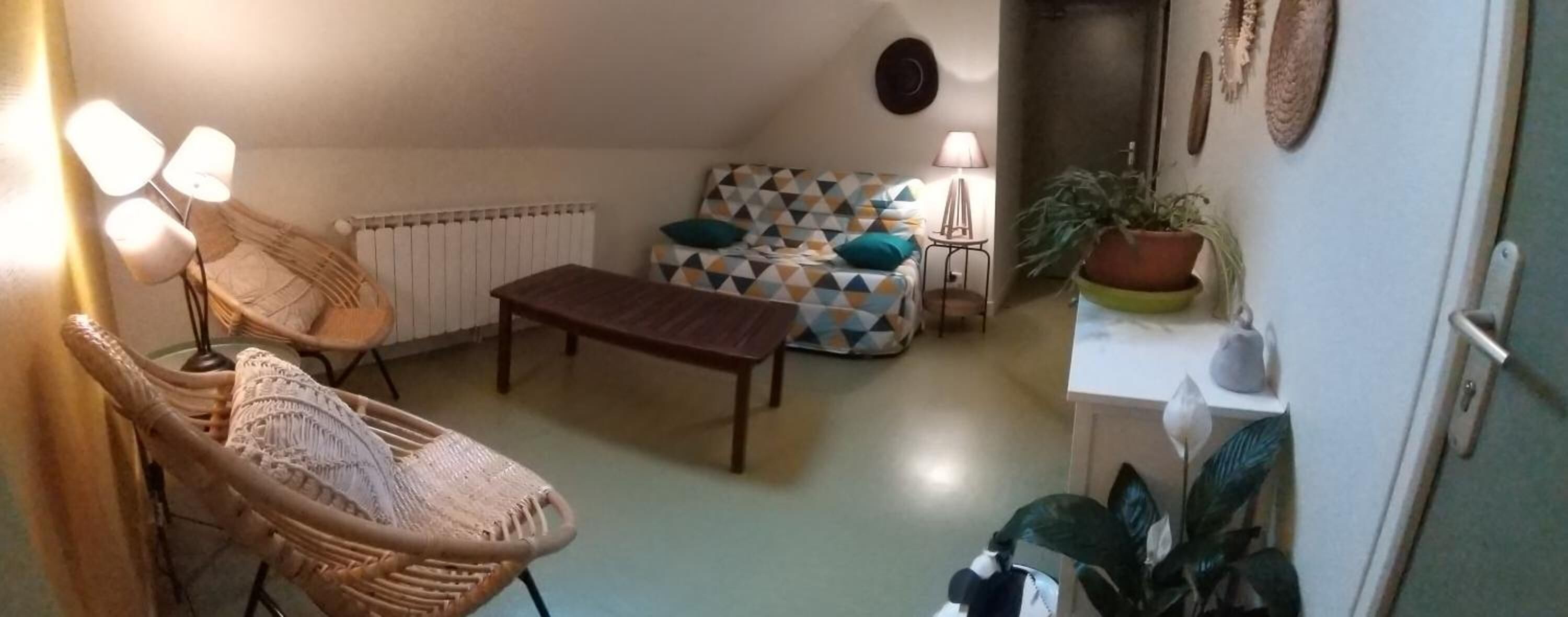 Una sala de estar acogedora con un sofá estampado, una mesa de centro de madera y sillas de mimbre.