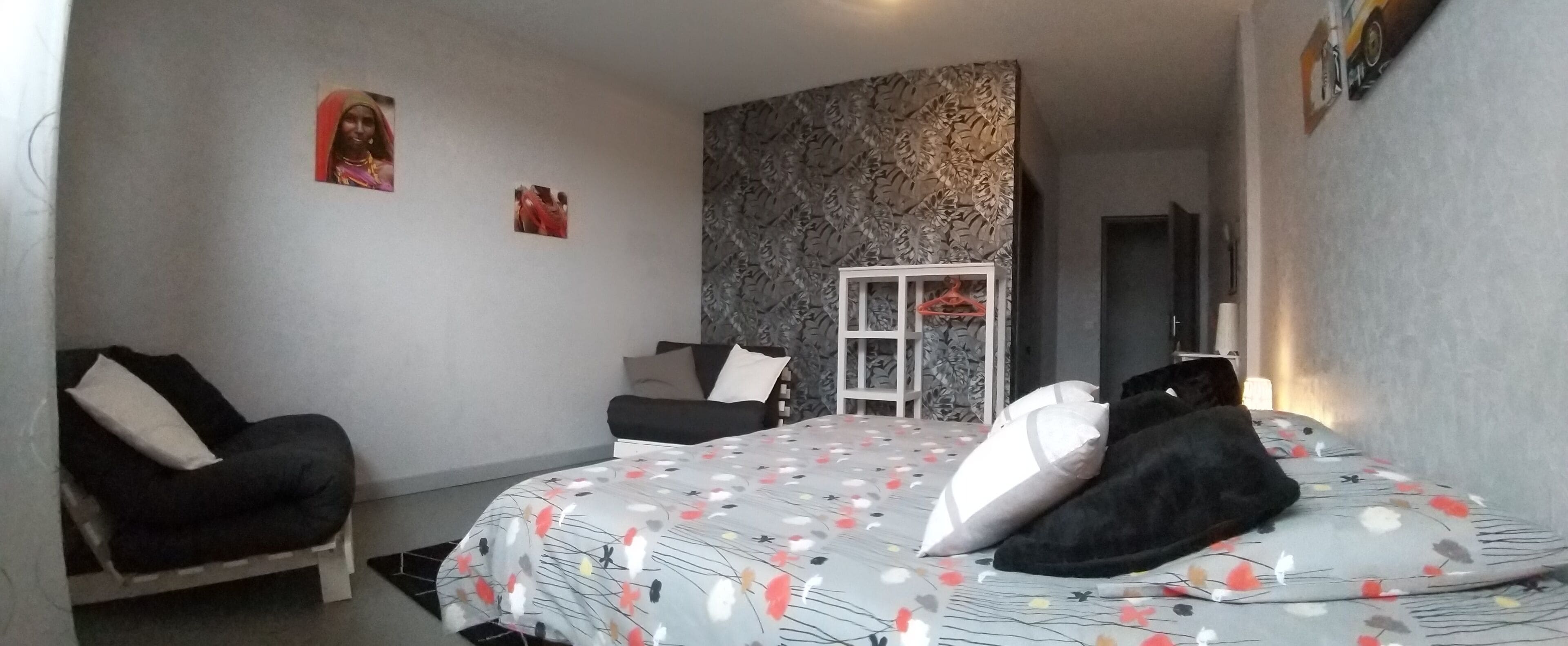 Ein Schlafzimmer mit einem Bett, einem Sessel, einem Schrank und einer Tür.