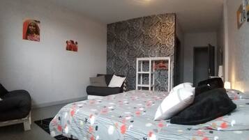 Ein Schlafzimmer mit einem Bett, einem Sessel, einem Schrank und einer Tür.