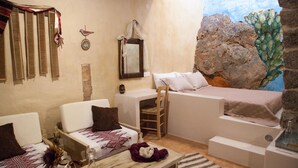 Une pièce confortable avec un lit, une chaise, une petite table et une fresque murale.