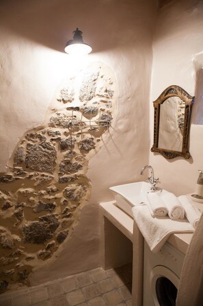 Ein Badezimmer mit Steinwand, Waschbecken, Spiegel und Handtuchhalter.