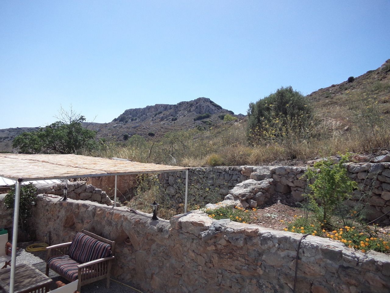A stone-walled outdoor area with a covered seating area and a small table.
