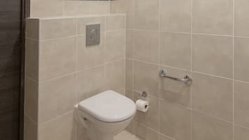 Une petite salle de bain moderne équipée de toilettes, d’un sèche-mains et d’un distributeur de serviettes en papier.