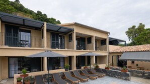 A modern two-story building with a pool area, including lounge chairs and umbrellas. - Casa di a Restonica (Corte)