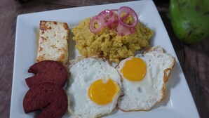 Um prato com ovos mexidos, torradas e carne vermelha.