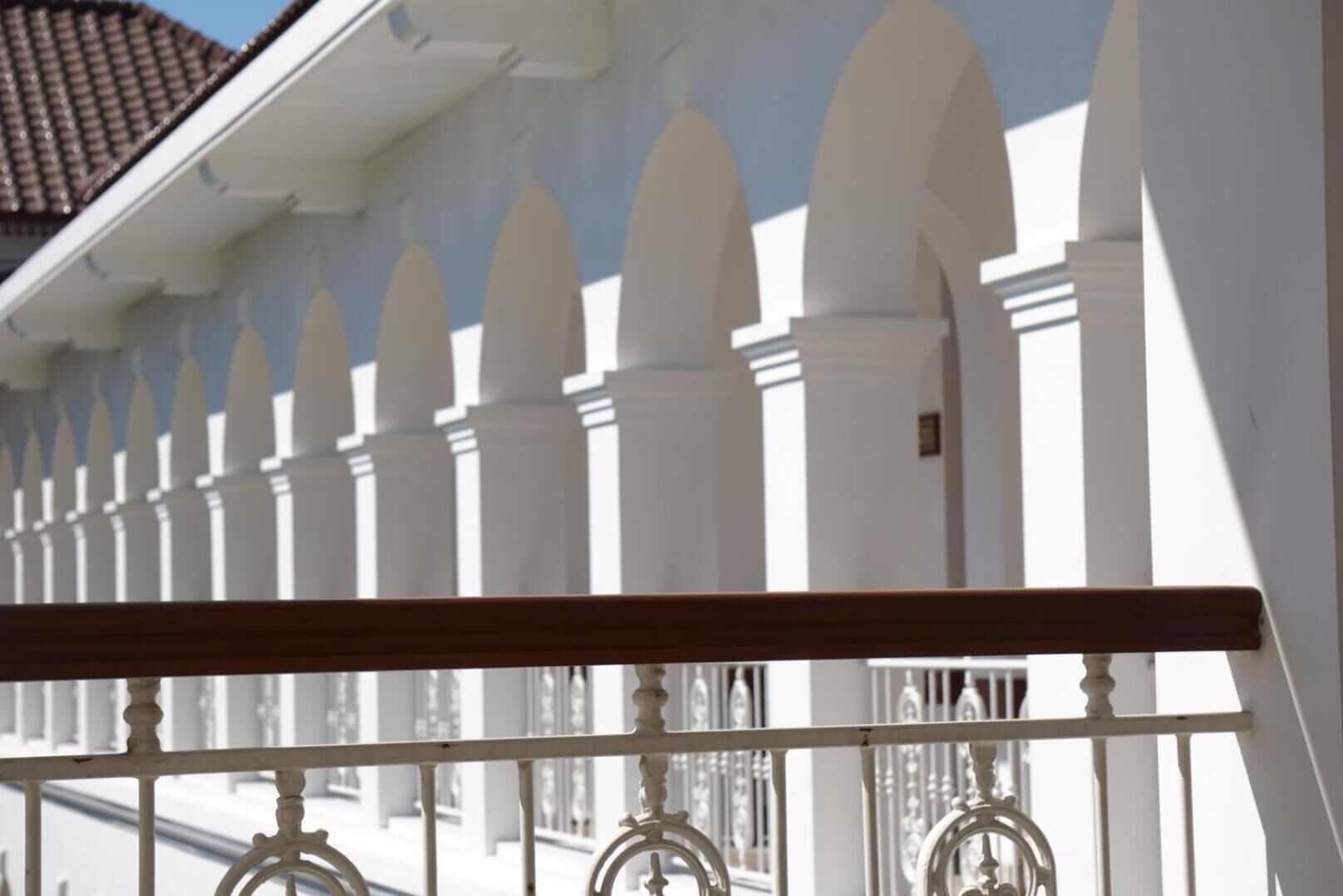 A white fence with pointed tops and a balcony railing.