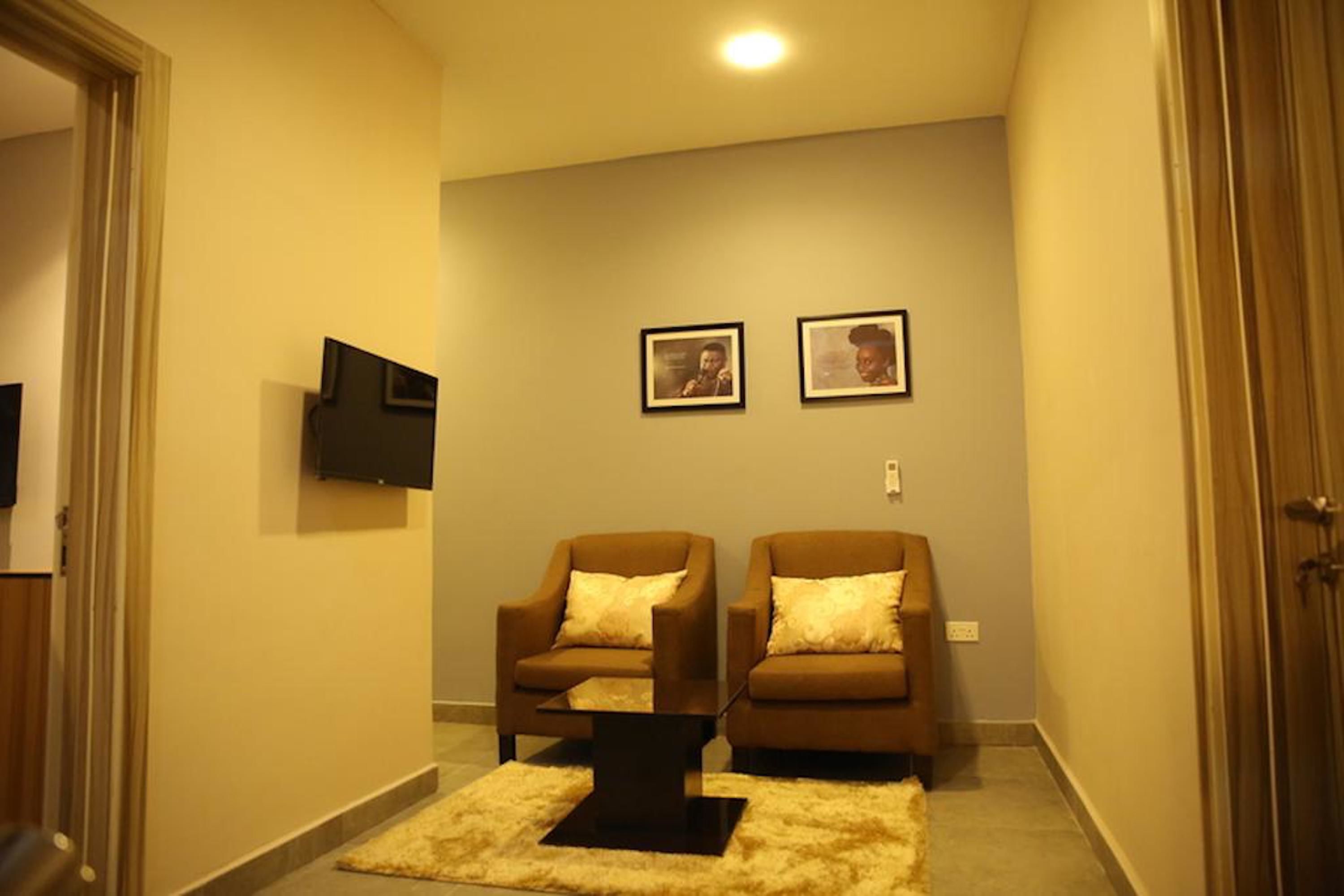 A living room with two brown armchairs, a black coffee table, and two framed pictures on the wall.