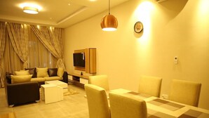 A living room with a sofa, coffee table, and dining table with chairs. - Kiniz Luxury Apartments (Uyo)