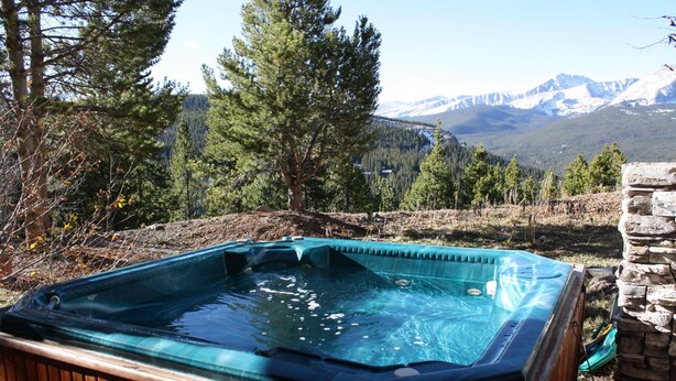 Un bain à remous situé dans un cadre naturel, avec une chaîne de montagnes en arrière-plan.