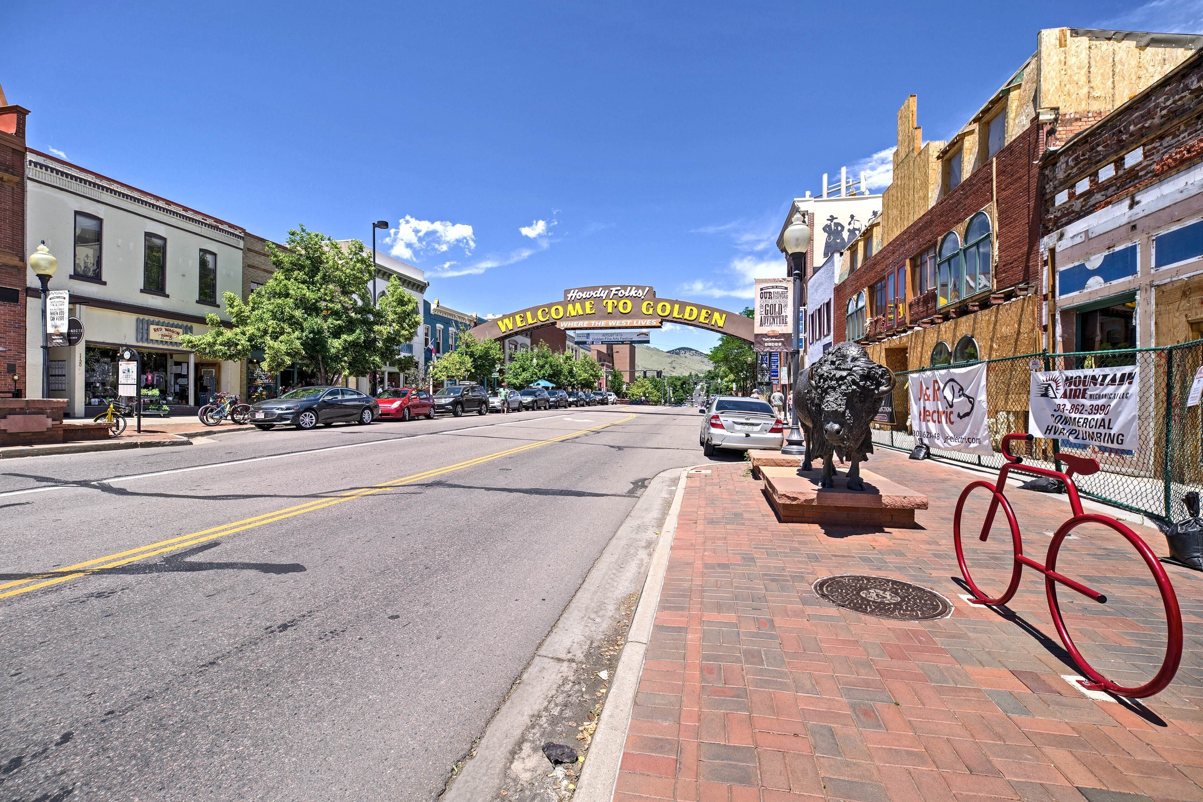 A street with a sign reading "Welcome to Golden" and a bicycle sculpture.