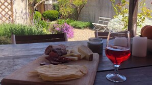 A wooden table with a cheese board, charcuterie, and a glass of red wine. - Charming house with beautiful garden, close to the beach. Free WiFi! (riola sardo)