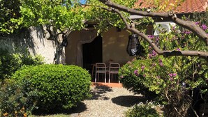 A garden pathway leading to a building with a tiled roof and a satellite dish. - Charming house with beautiful garden, close to the beach. Free WiFi! (riola sardo)