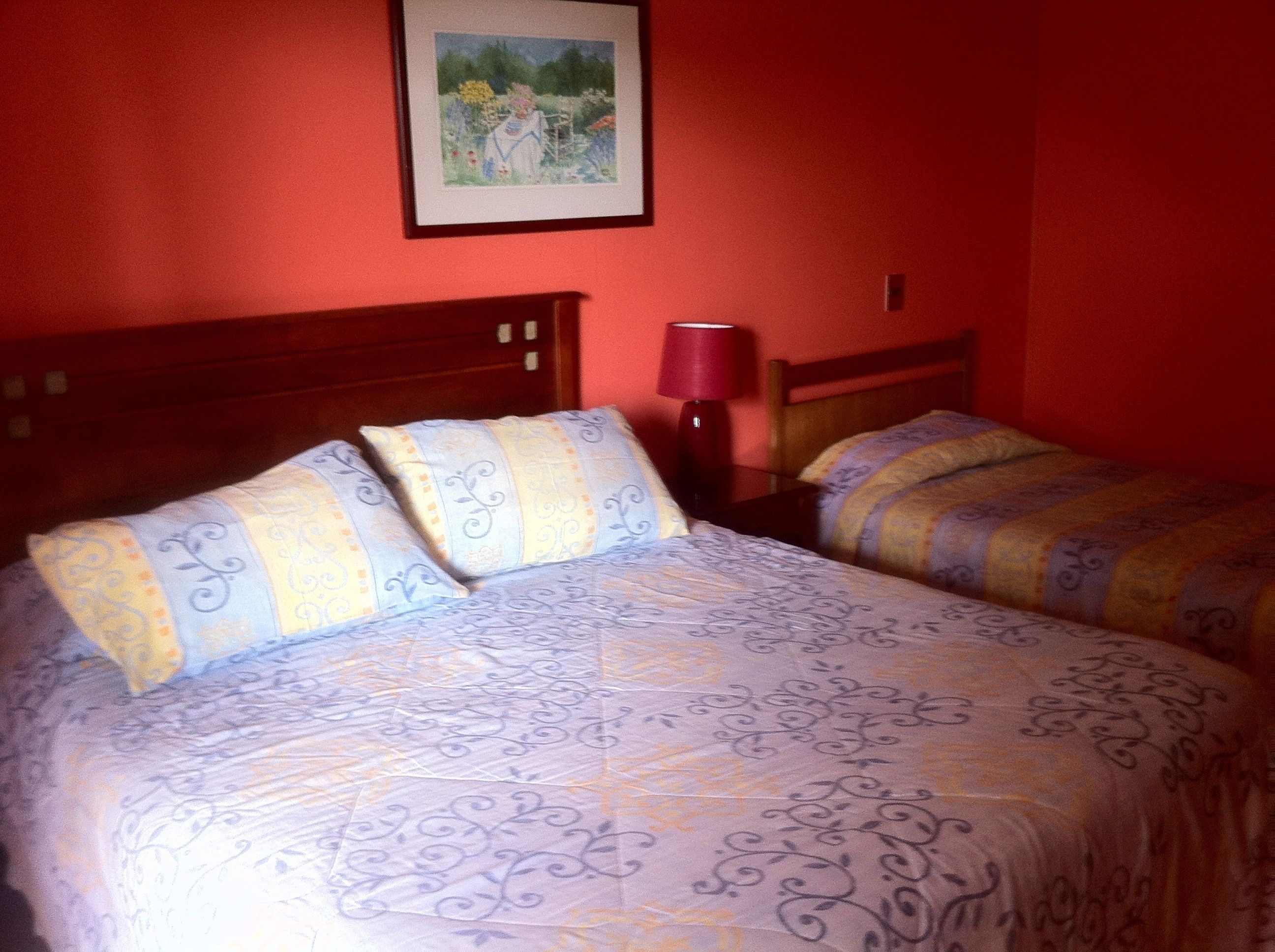 A hotel room with two beds, each with patterned bedding and a wooden headboard.