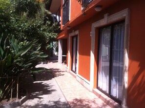 A building with a red exterior, large windows, and a tiled walkway. - Hotel del Cid (La Serena)