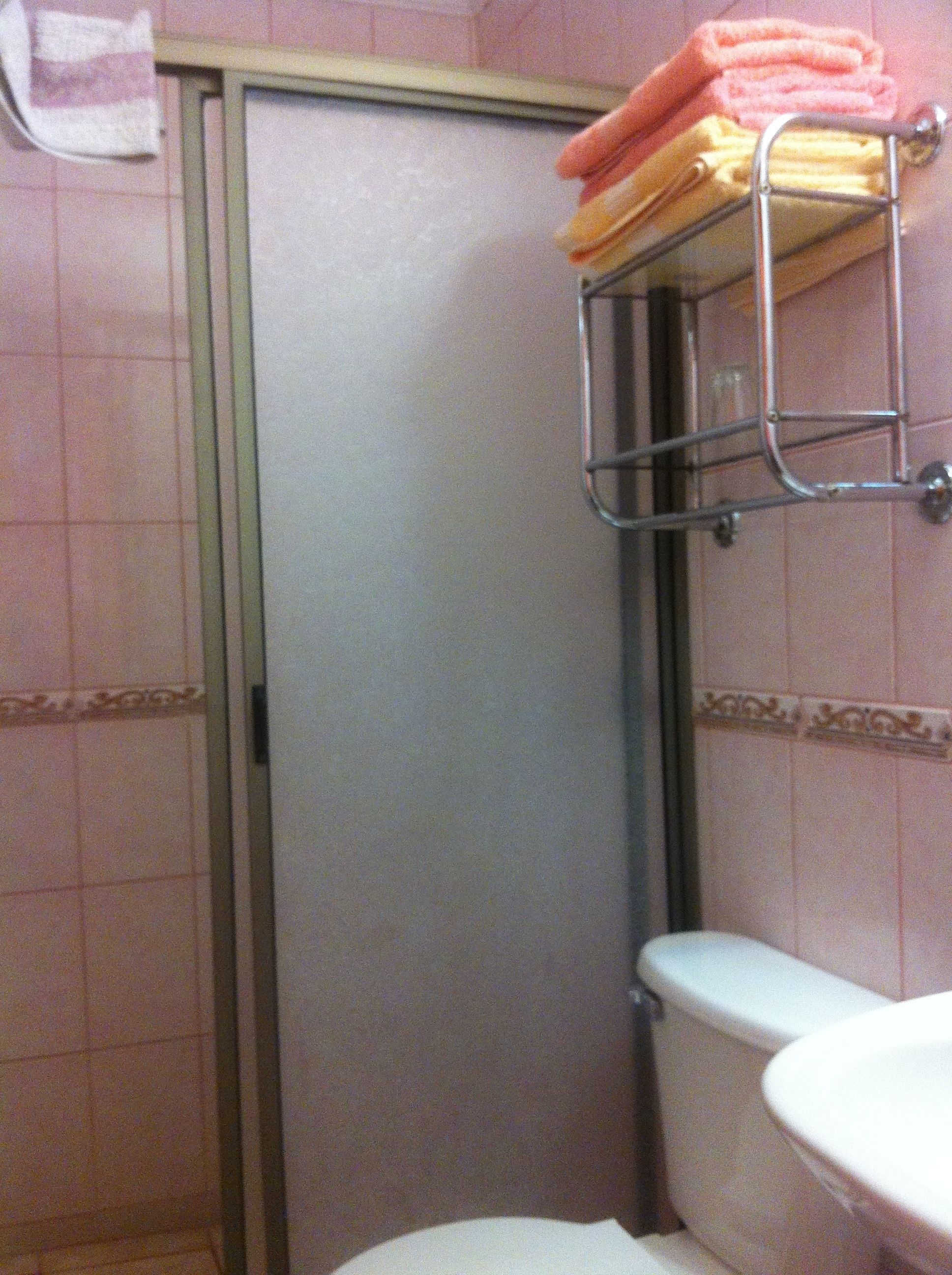 A bathroom with a toilet, a sink, and a towel rack with folded towels.