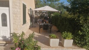 An outdoor patio with a table and chairs, surrounded by potted plants and a white umbrella. -  Home in Serene Village-Vineyards Views-Central To All Attractions-Highway   (Zemunik Gornji)