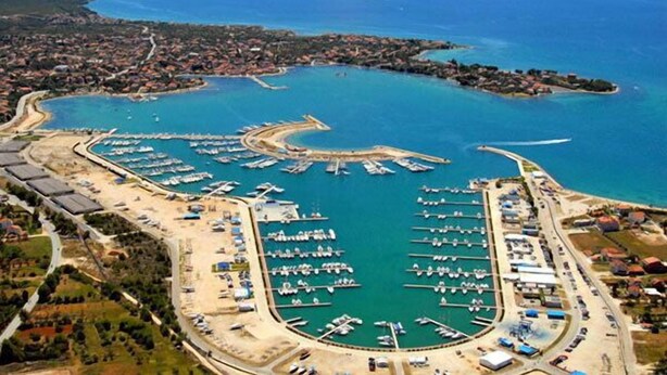 An aerial view of a coastal marina with numerous docks and boats, surrounded by residential areas and a large body of water. -  Home in Serene Village-Vineyards Views-Central To All Attractions-Highway   (Zemunik Gornji)