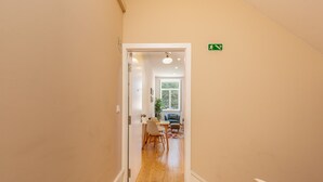 A hallway with wooden flooring leading to a dining area with a table and chairs.