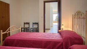 Ein Schlafzimmer mit einem Bett, zwei Stühlen, einem Kleiderschrank und einer Tür, die auf einen Balkon führt.