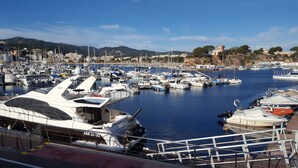 A marina with various boats docked, a clear sky, and a hilly landscape in the background. - CALA DEL PI RESIDENTIAL APARTMENT (TREUMAL CENTER) PLATJA D¨ARO (Platja D Aro)