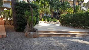 A landscaped area with palm trees, a pool, and a building in the background. - CALA DEL PI RESIDENTIAL APARTMENT (TREUMAL CENTER) PLATJA D¨ARO (Platja D Aro)