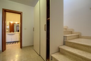 A hallway with a bathroom, a wardrobe, and a staircase.