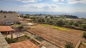 A coastal property with stone buildings, a garden, and a view of the sea.
