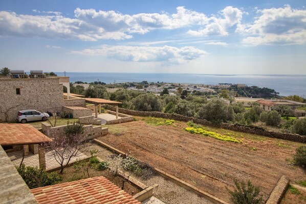 A coastal property with stone buildings, a garden, and a view of the sea.