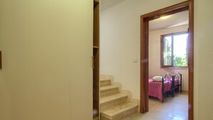 A staircase leading to a bedroom with a window and a bed.