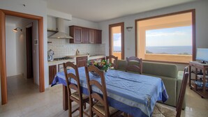 A compact kitchen with a dining area, a view through a large window, and a small seating area.
