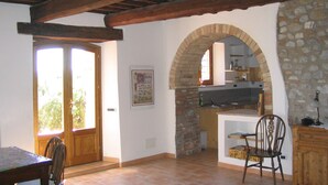 A rustic kitchen with stone walls, wooden beams, and a tiled floor.