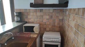 Eine kleine Küche mit Spüle, Mikrowelle, Herd und Kaffeemaschine.