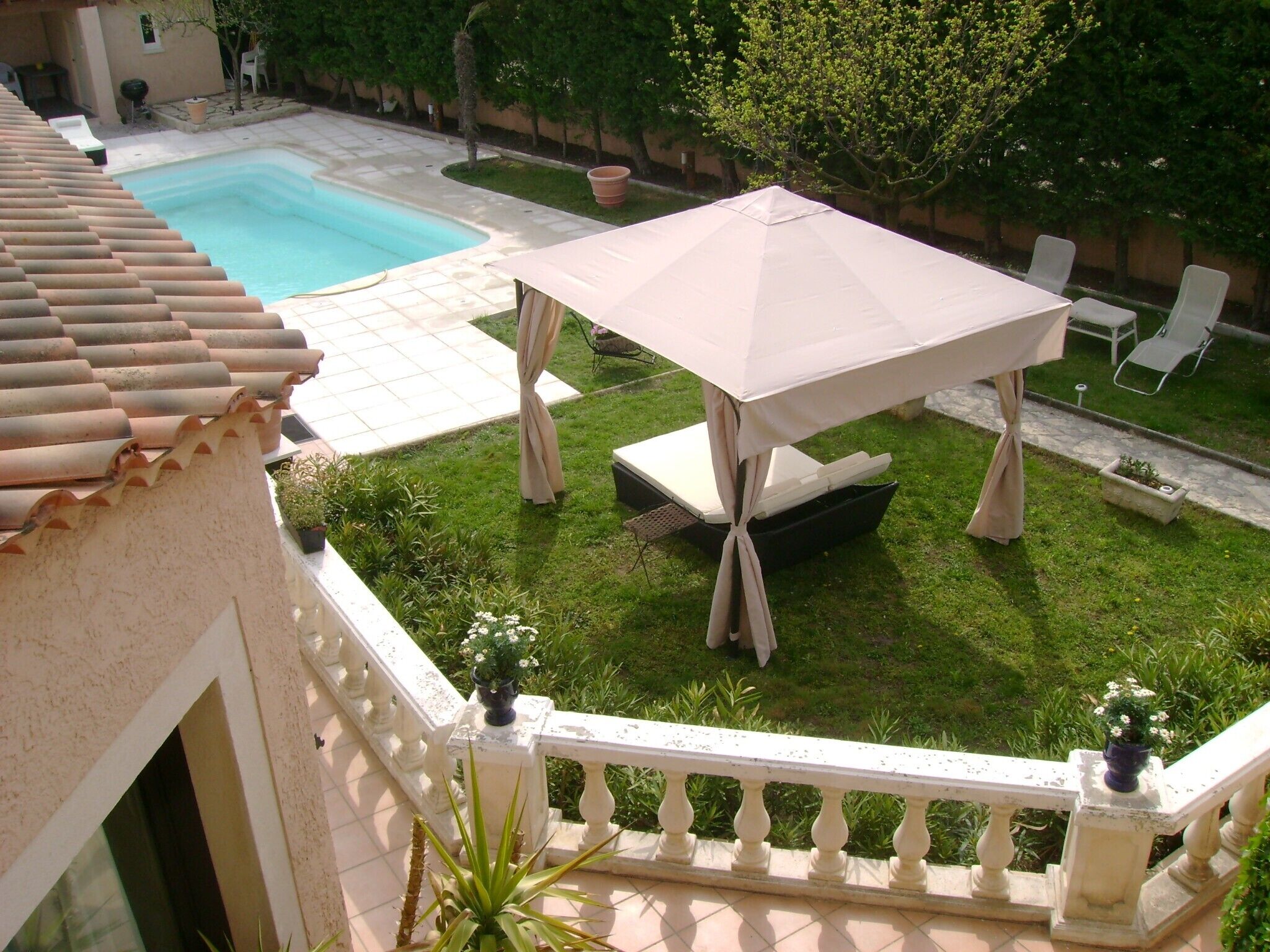 A courtyard with a swimming pool, a covered table, and lounge chairs.