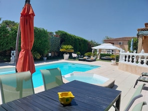 A pool area with lounge chairs, a table, and a yellow decorative item.