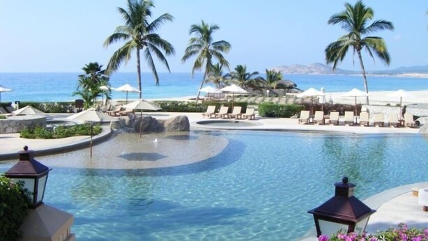 A pool area with lounge chairs and palm trees, overlooking a beach. - Oceanfront Resort Beach Paradise! Great Reviews,  Modern Remodel great location! (San Jose Del Cabo)