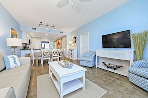 A modern living room with a dining area, a TV mounted on the wall, and a fireplace.