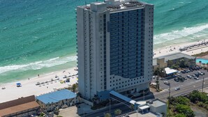 Un hôtel de grande hauteur offrant une vue sur la plage, doté d’une piscine et d’un parking.