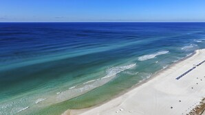 Une plage aux eaux turquoise et limpides, bordée d’un rivage sablonneux.