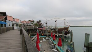 Eine Holzstege, der sich über ein Gewässer erstreckt, mit einer Bar, die rote Sonnenschirme und ein Schild für 'Eddie's Dockside Bar' zeigt.