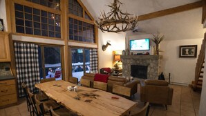 Amplia sala de estar con una gran mesa de comedor de madera, sofás de cuero y una chimenea de piedra.
