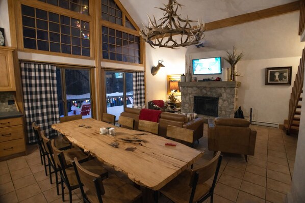 Amplia sala de estar con una gran mesa de comedor de madera, sofás de cuero y una chimenea de piedra.