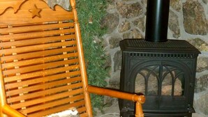 Un banco de madera con diseño de estrella, un pequeño árbol de Navidad y un estufa de leña negra en una habitación rústica.
