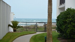 A pathway leading to a gated area with a view of the ocean. - Beachfront condo: Create some memories! (South Padre Island)