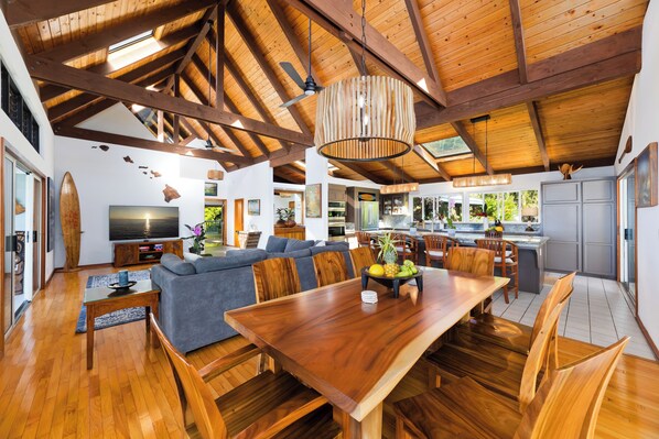 A spacious living area with a wooden dining table, a sofa, and a TV. - Maka Nui Estate/ Luxury Big Island Ocean View Home Above Kealakekua Bay (Captain Cook)