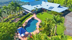 A large house with a pool, surrounded by lush greenery and a view of the ocean. - Maka Nui Estate/ Luxury Big Island Ocean View Home Above Kealakekua Bay (Captain Cook)
