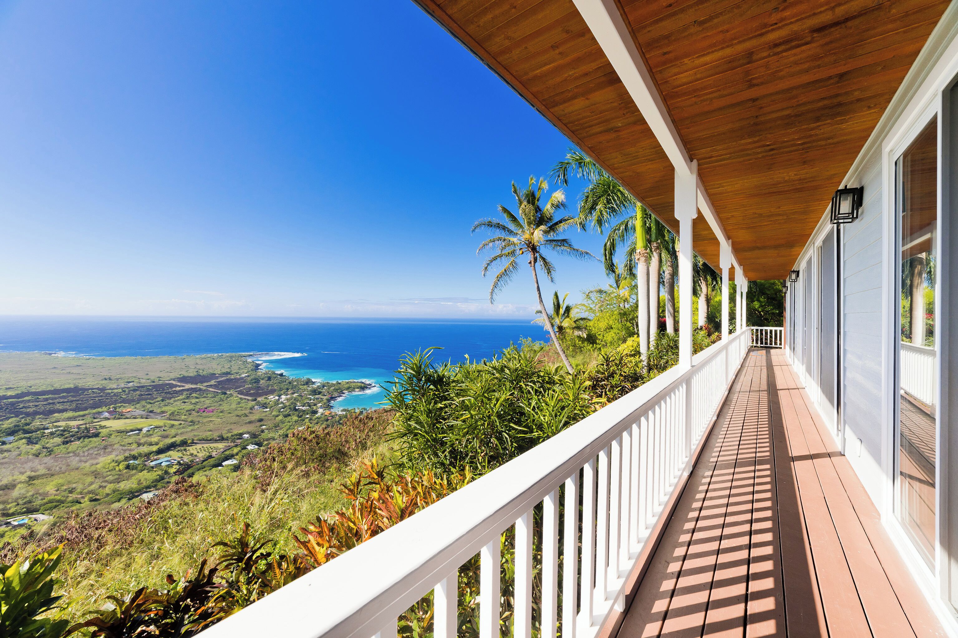 A wooden deck with a view of the ocean and hills.